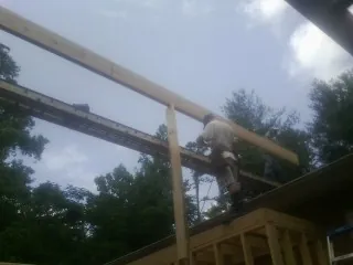 Carpenter setting a ridge beam over a new addition frame — Ice Dam Removal by Roofing Brothers in Kinston