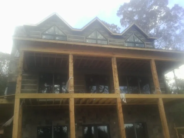 Dormers and porch framing on a large log home under construction — Roof Coating work by our crew in Kinston