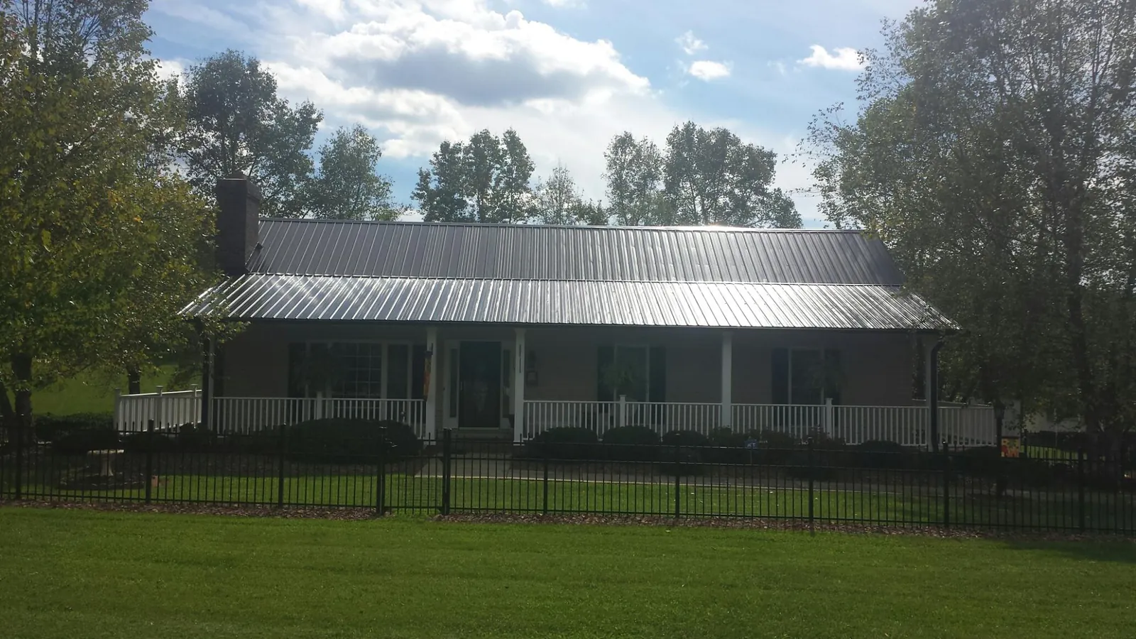 Gray metal roof on a brick ranch with a full width front porch — Gutter Guard Installation work by our crew in Kinston
